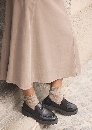 Detailbild von einem braunen Rock und schwarzen Schuhen