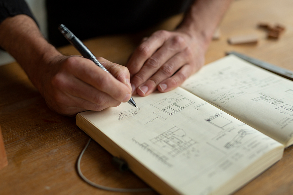 Designer macht Notizen zum Produkt in seinem Notizbuch