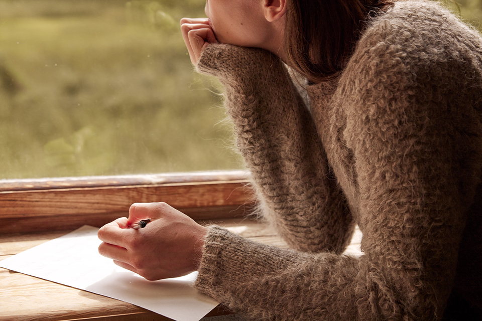 Person schreibt konzentriert Bewerbung oder Notizen am Tisch