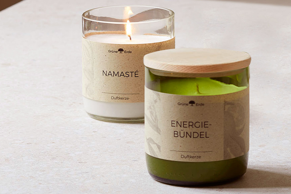 Zwei Duftkerzen stehen hintereinander auf einer weißen Oberfläche