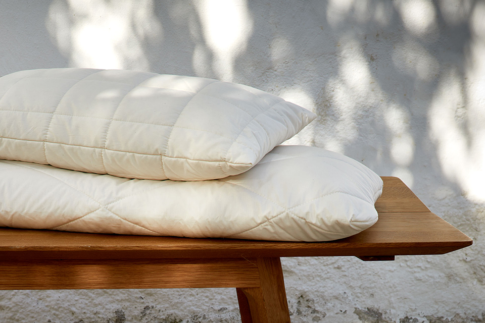 Zwei hochwertige Kopfkissen auf einer Holzbank im Freien