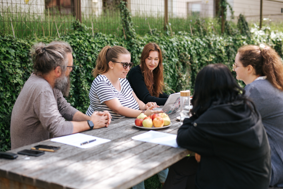 Teammeeting im Freien mit mehreren Personen am Tisch