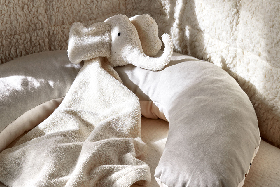 Nackenkissen und Stoffelefant in einem Kinderbett