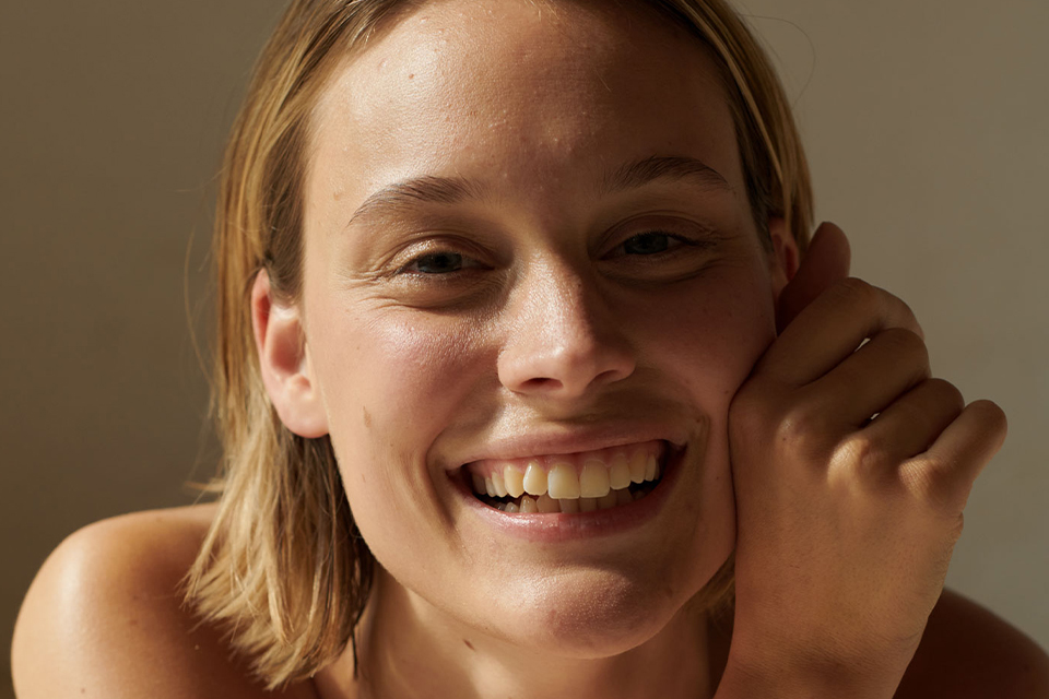 Lächelnde Frau zeigt gesunde Zähne in warmem Licht