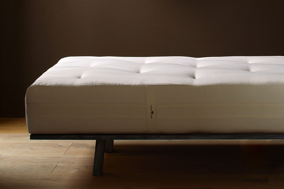 Eine ökologische Naturmatratze liegt auf einem dunklen Holzgestell