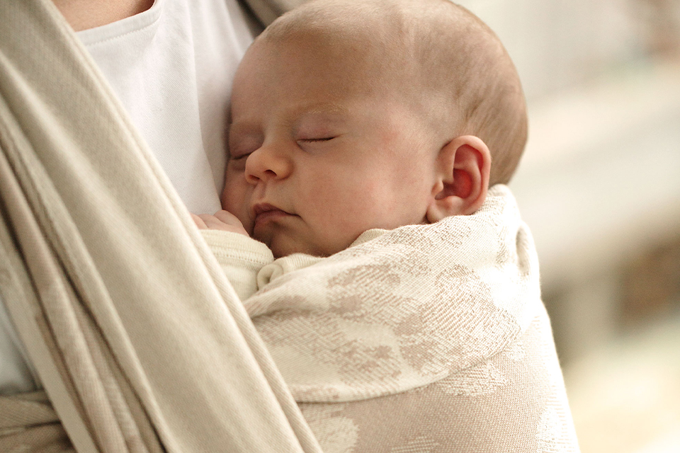 Ein Baby schläft im Tragetuch