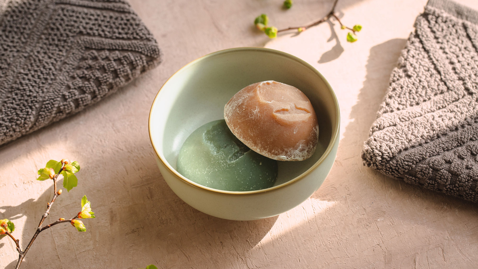 Eine grüne und eine braune feste Seife in einer Keramikschüssel