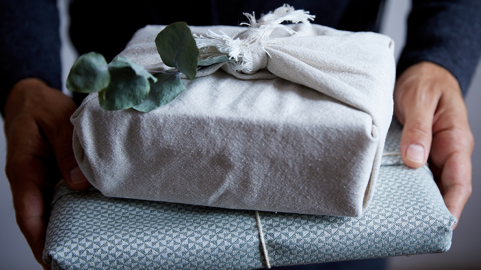 Hände halten einen Stapel aus zwei Geschenken