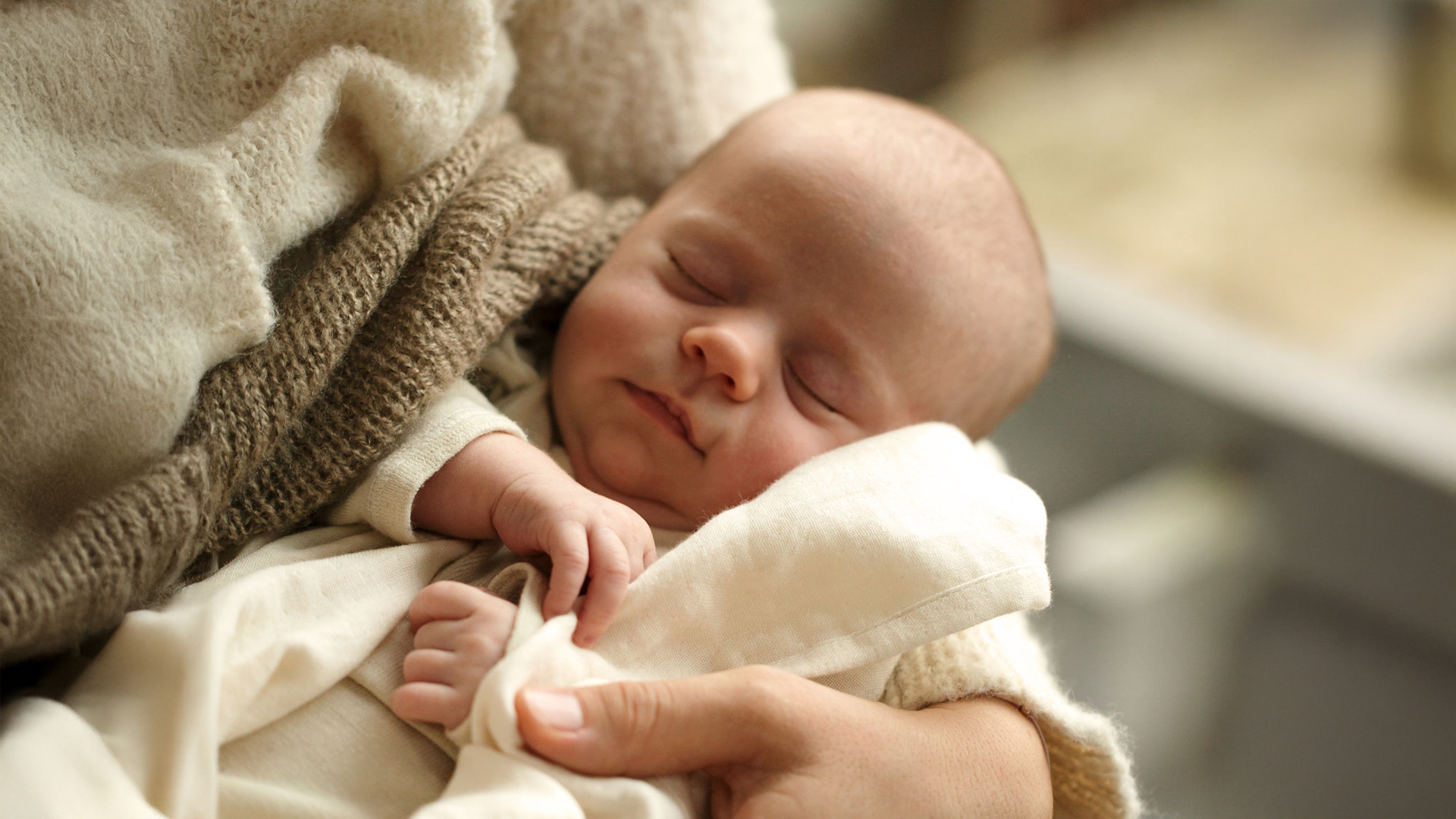 Ein schlafendes Baby in den Armen seiner Mutter