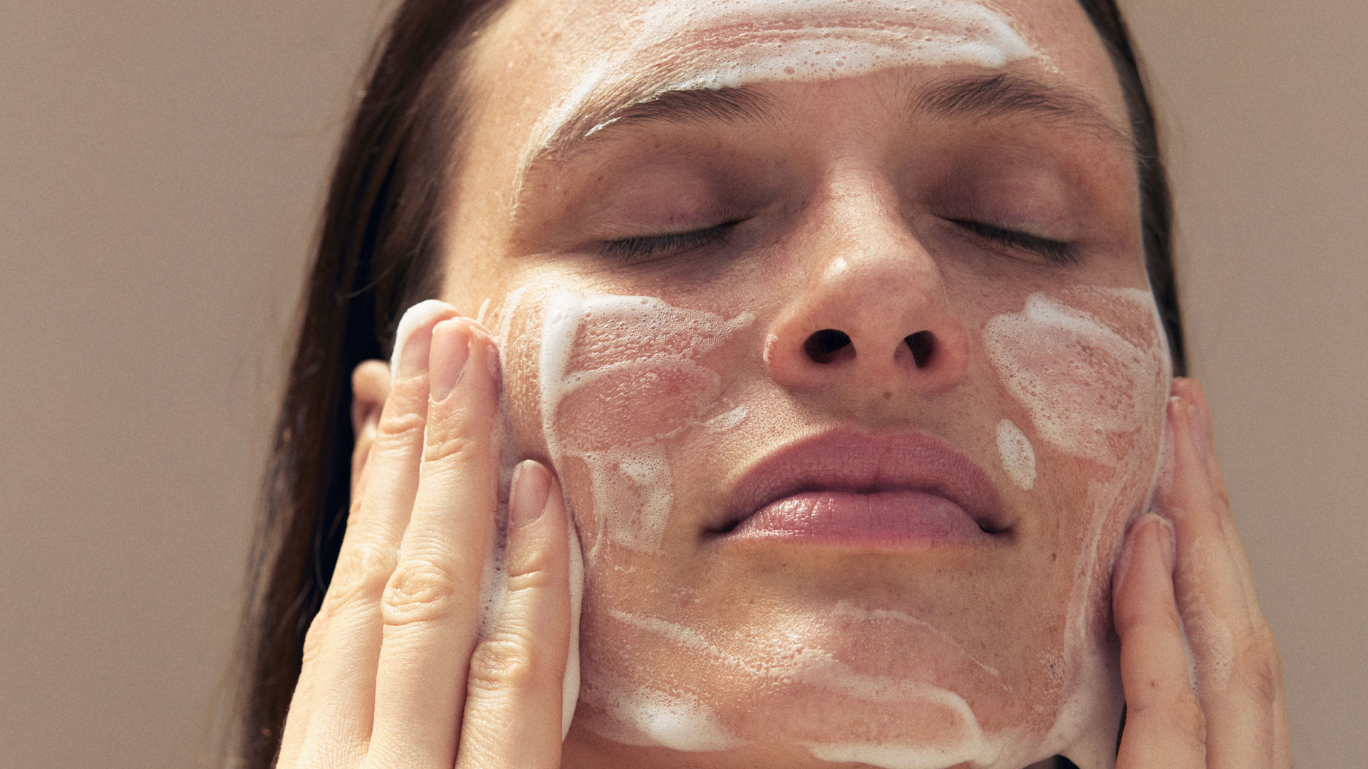 Frau reinigt ihr Gesicht mit Reinigungsschaum