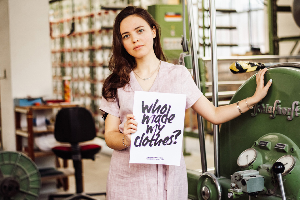 Frau trägt ein Schild mit der Aufschrift who made my clothes