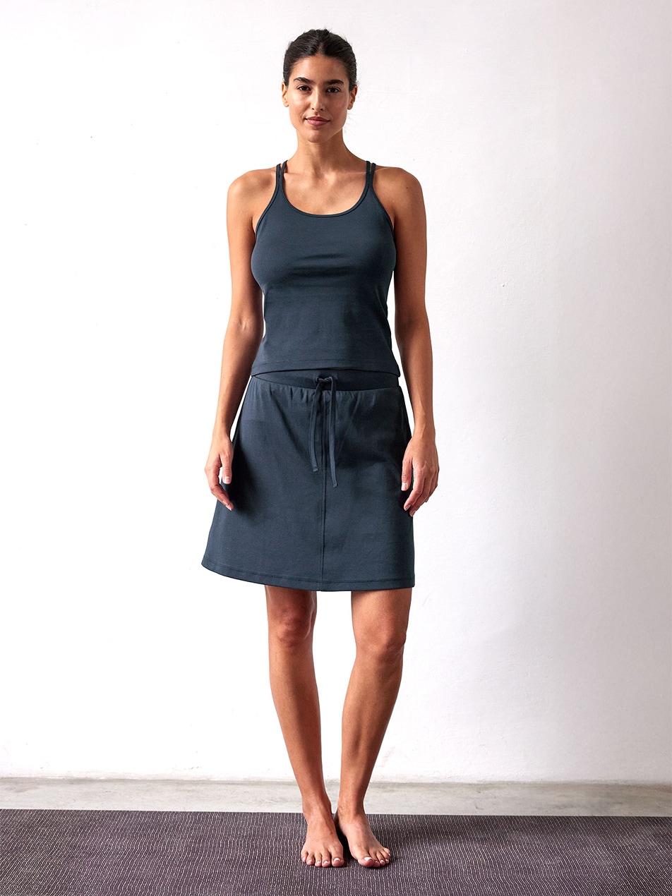 Frau trägt dunkles Top und Rock und steht barfuß