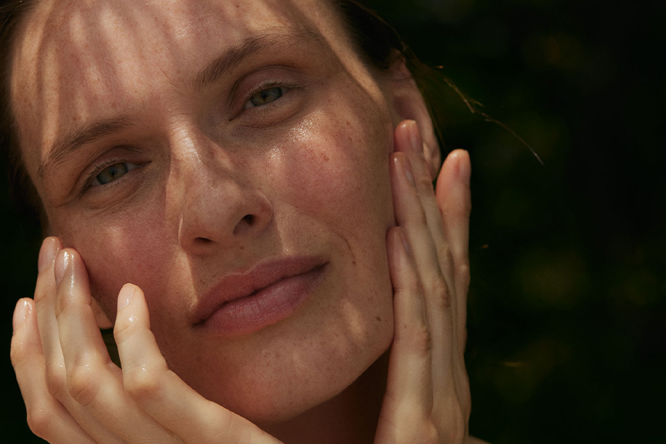 Frau berührt ihre Wangen mit den Händen