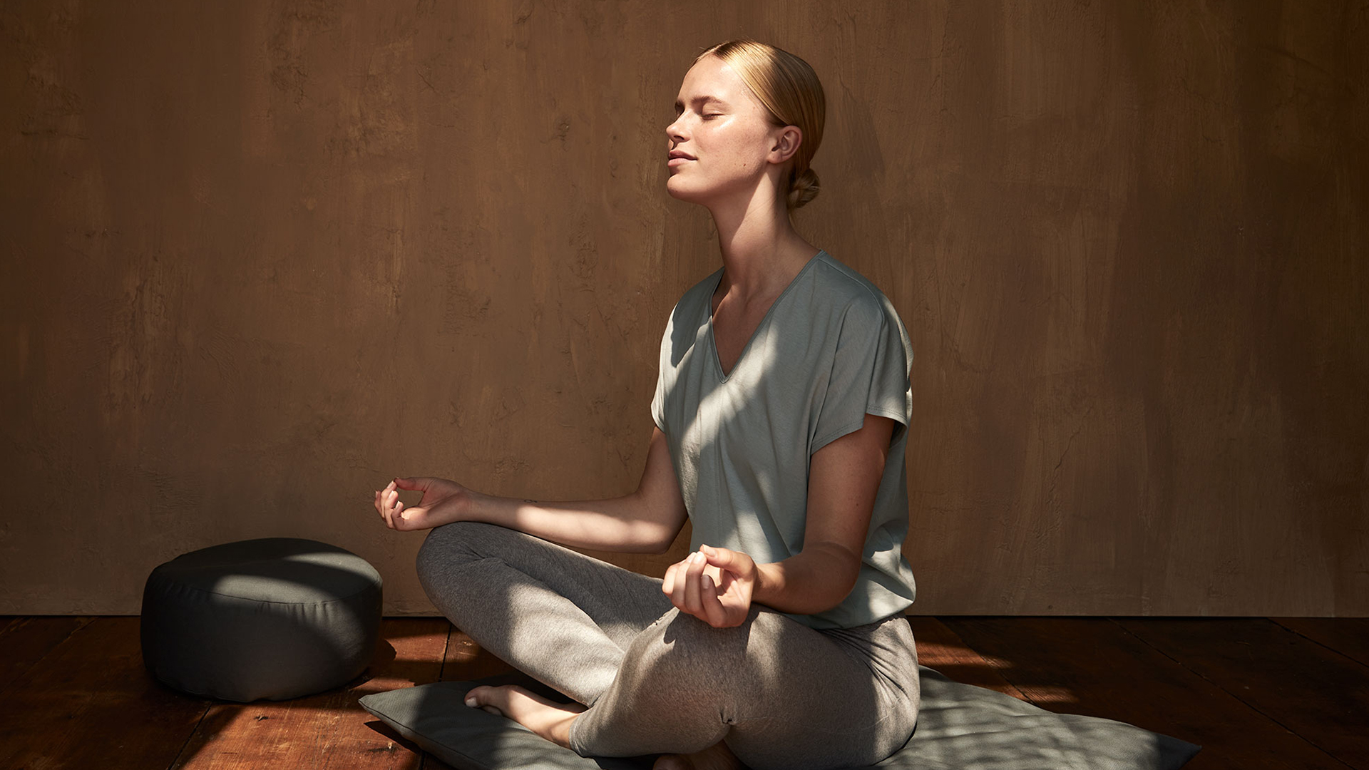 Frau meditiert ruhig in warmem Raum mit geschlossenen Augen