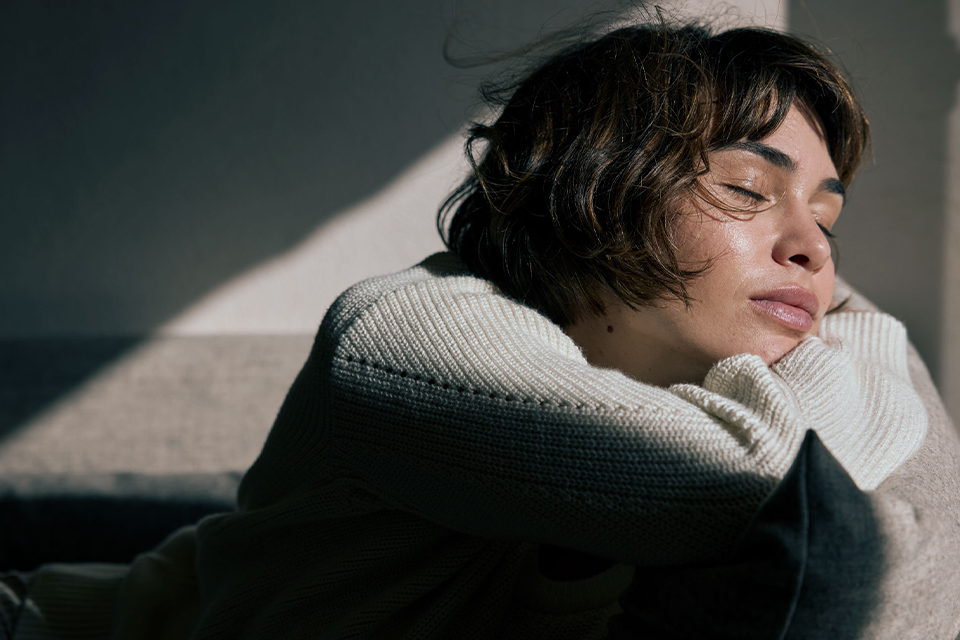 Entspannte Frau ruht mit geschlossenen Augen im sanften Licht