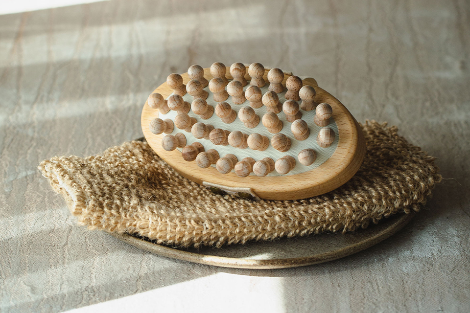 Holz-Massagebürste auf Naturfasern, warmes Licht, Wellness-Stimmung