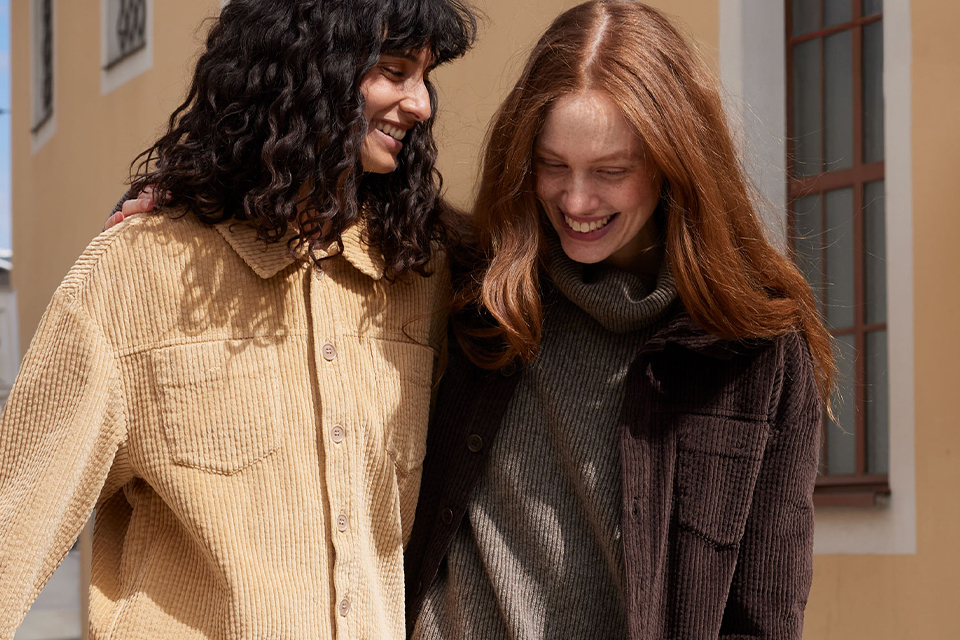 Zwei Freundinnen lachen gemeinsam draußen und genießen ihre Zeit