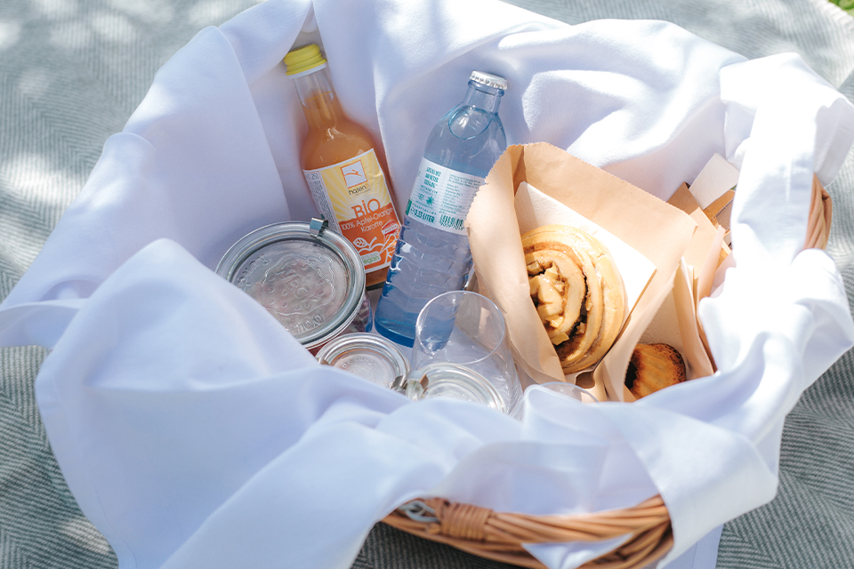 Picknickkorb mit Getränken und Gebäck in heller Umgebung