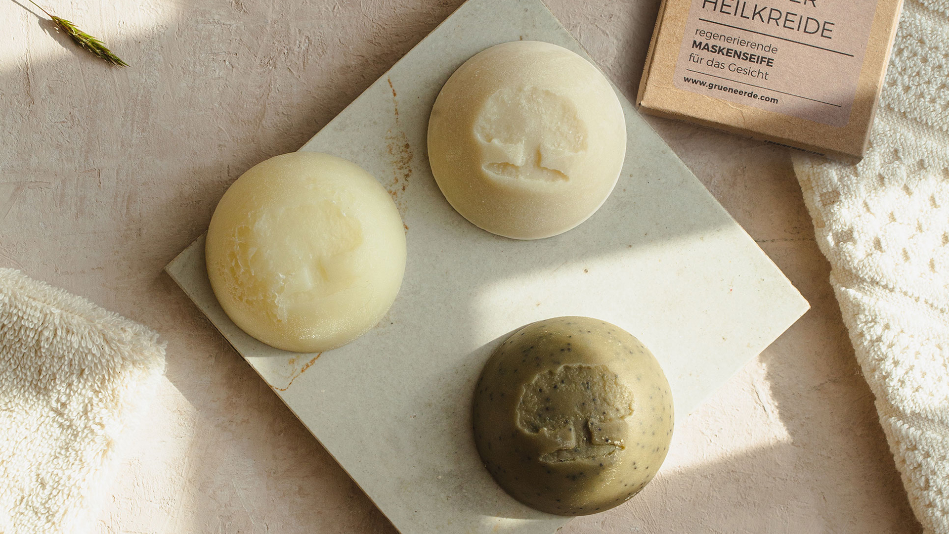 Zwei feste Seifen und ein Bürstchen mit einem dekorativen Blümchen