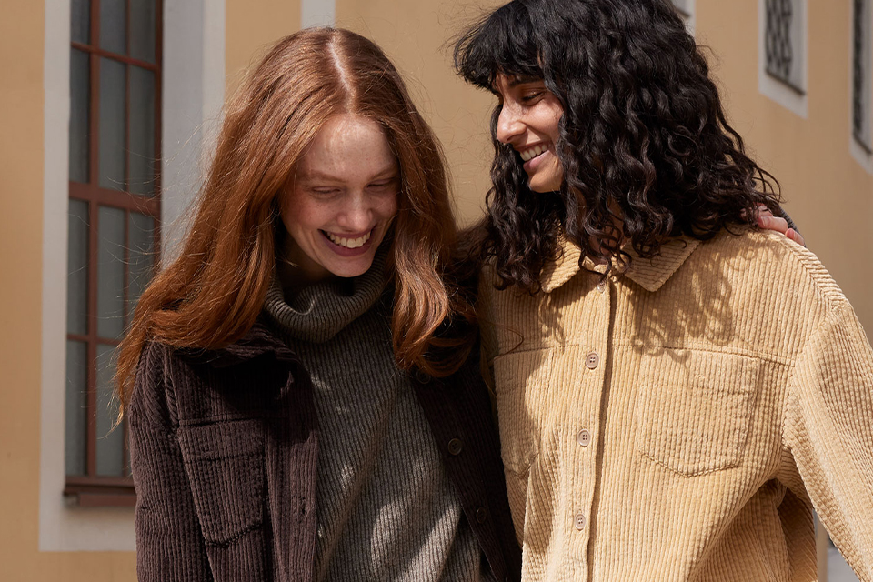 Zwei Frauen gehen Arm in Arm und lachen zusanne,