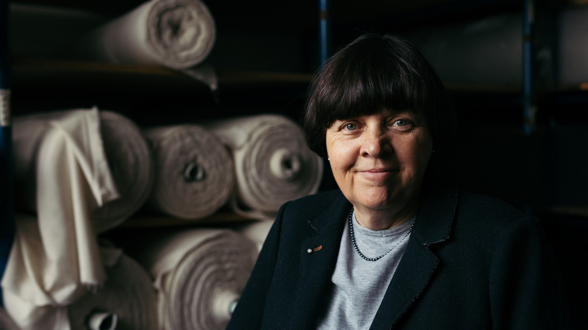 Lächelnde Frau steht vor Stoffrollen