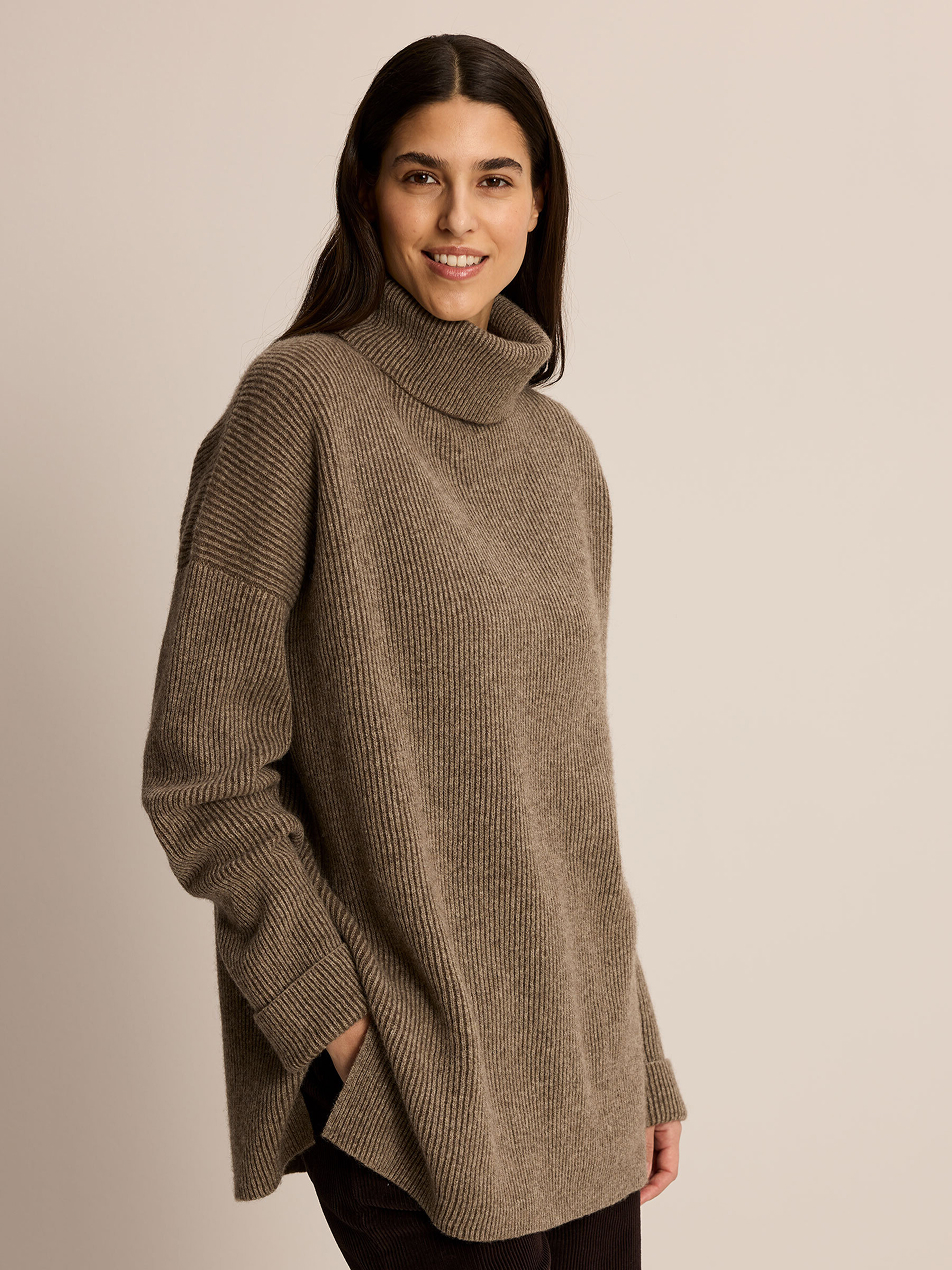 Lächelnde Frau trägt einen dunkelbraunen Pullover