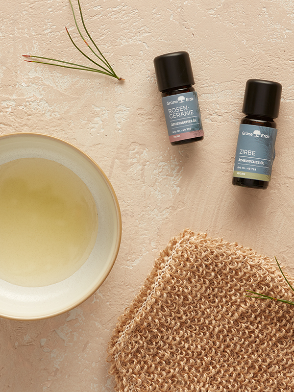 Basisöl und ätherische Öle neben einer Schale mit Öl