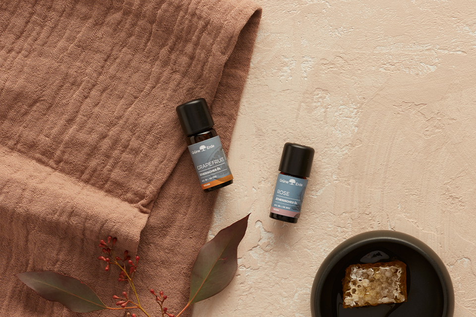 Ätherische Öle auf Stoff mit Honig und Blättern stilvoll arrangiert