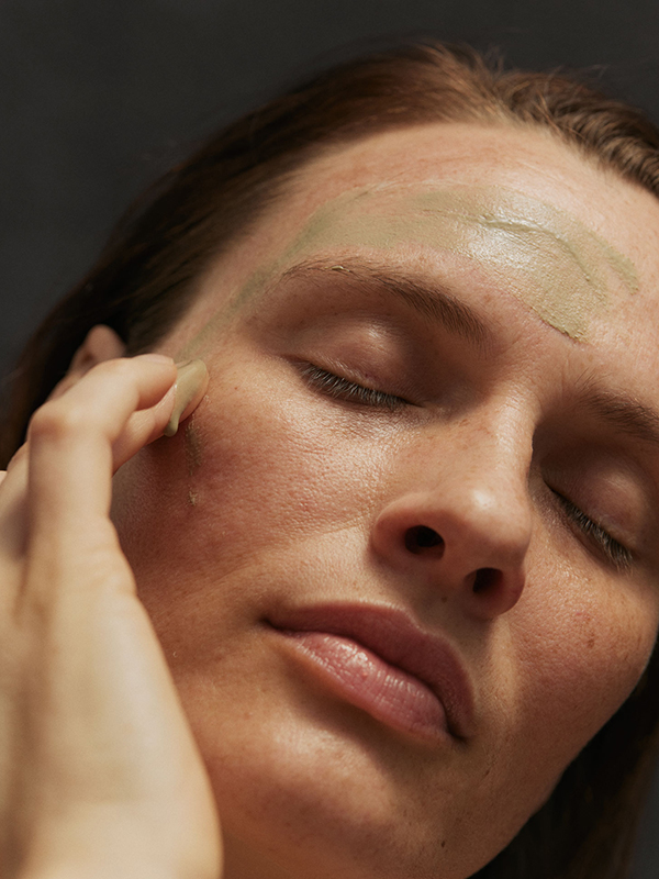 Frau mit geschlossenen Augen trägt Gesichtsmaske auf