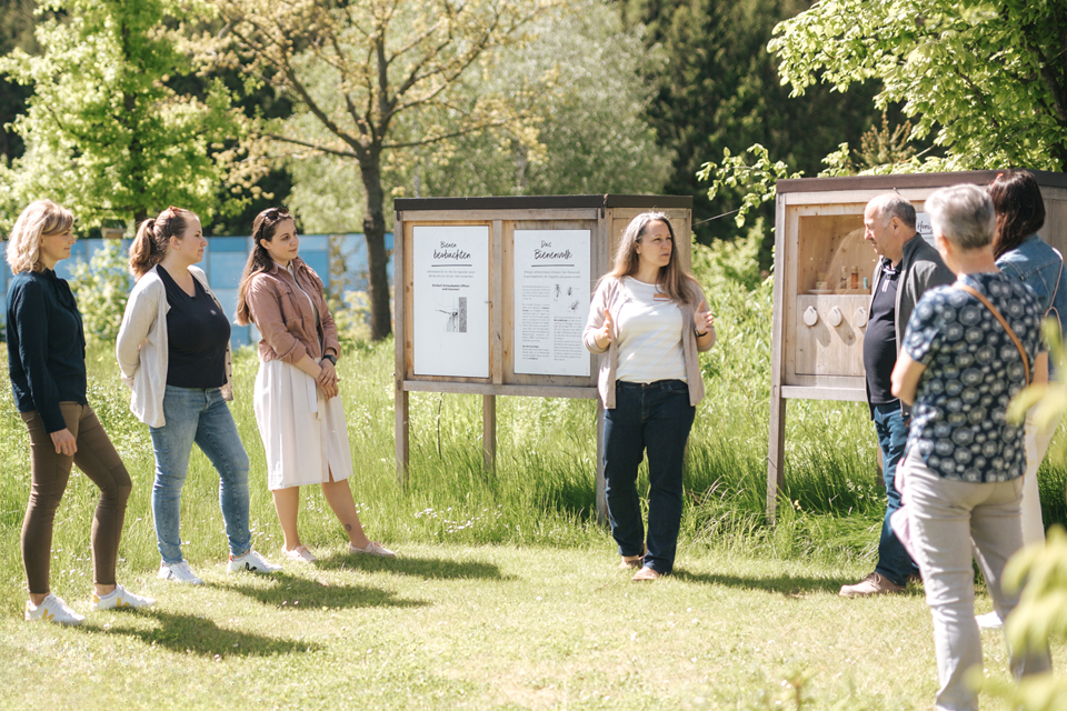 Gruppe steht im Freien vor Infotafeln bei Führung