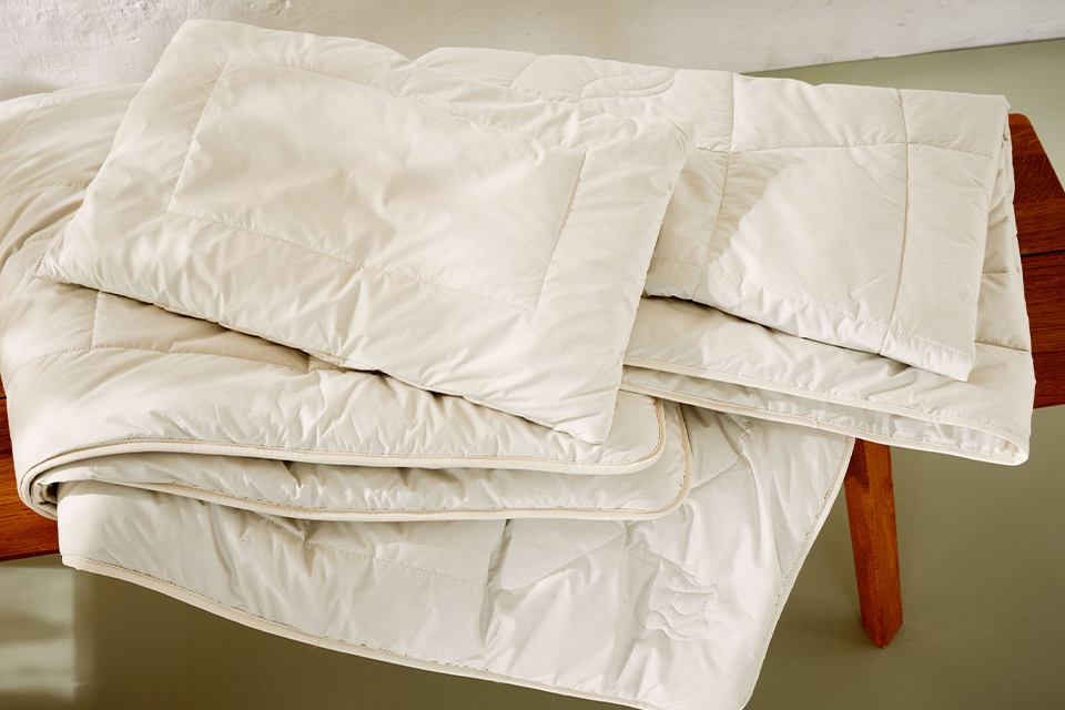 Drei Schlafdecken liegen gefaltet auf einer Holzbank