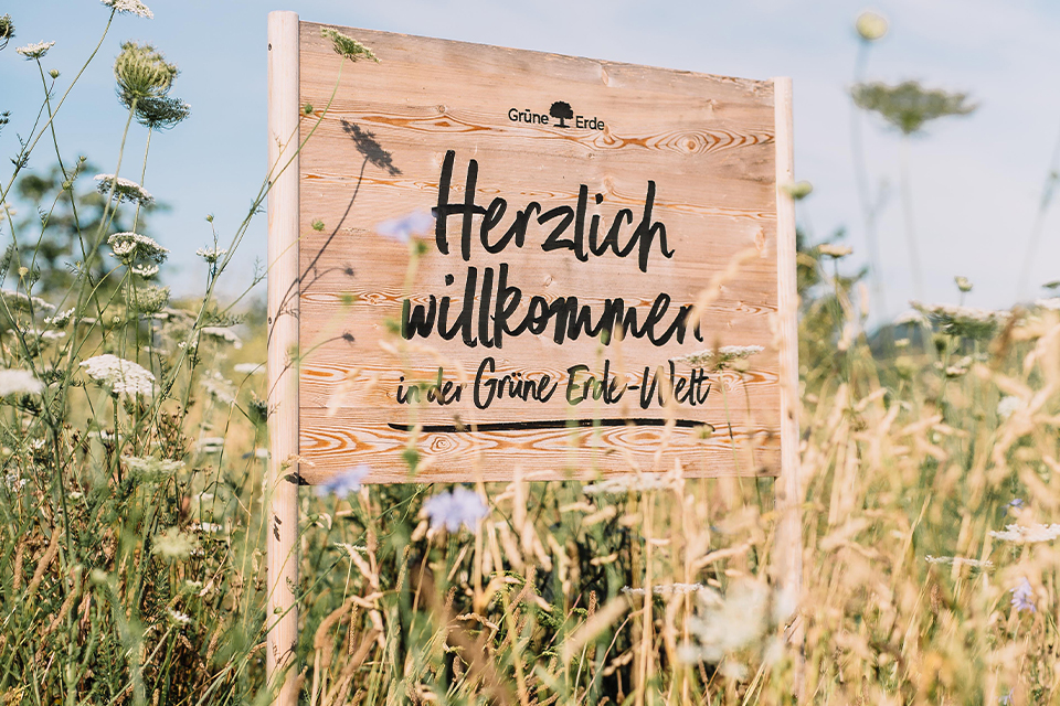 Holztafel mit der Aufschrift Herzlich Willkommen in der Grünen Erde Welt