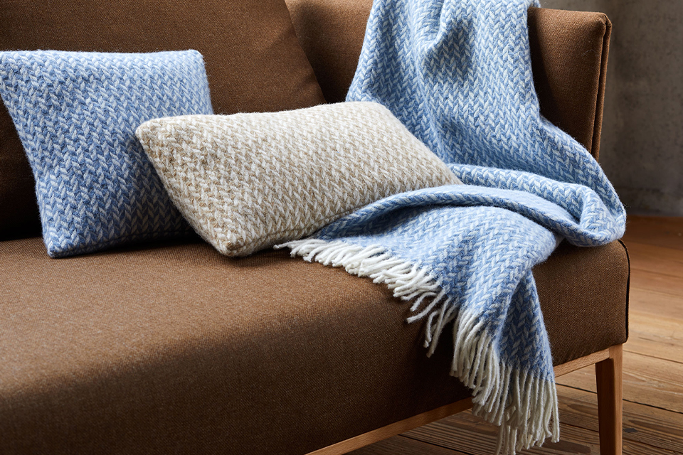 Zierkissen und Wohndecke auf einem braunen Sofa liegend