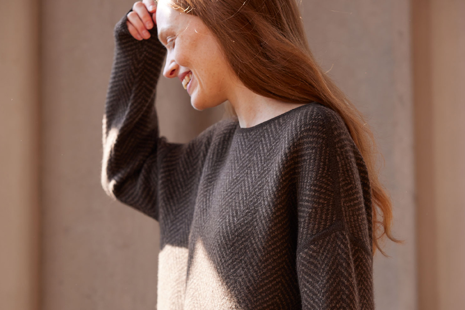 Frau lächelt in einem braunen Pullover