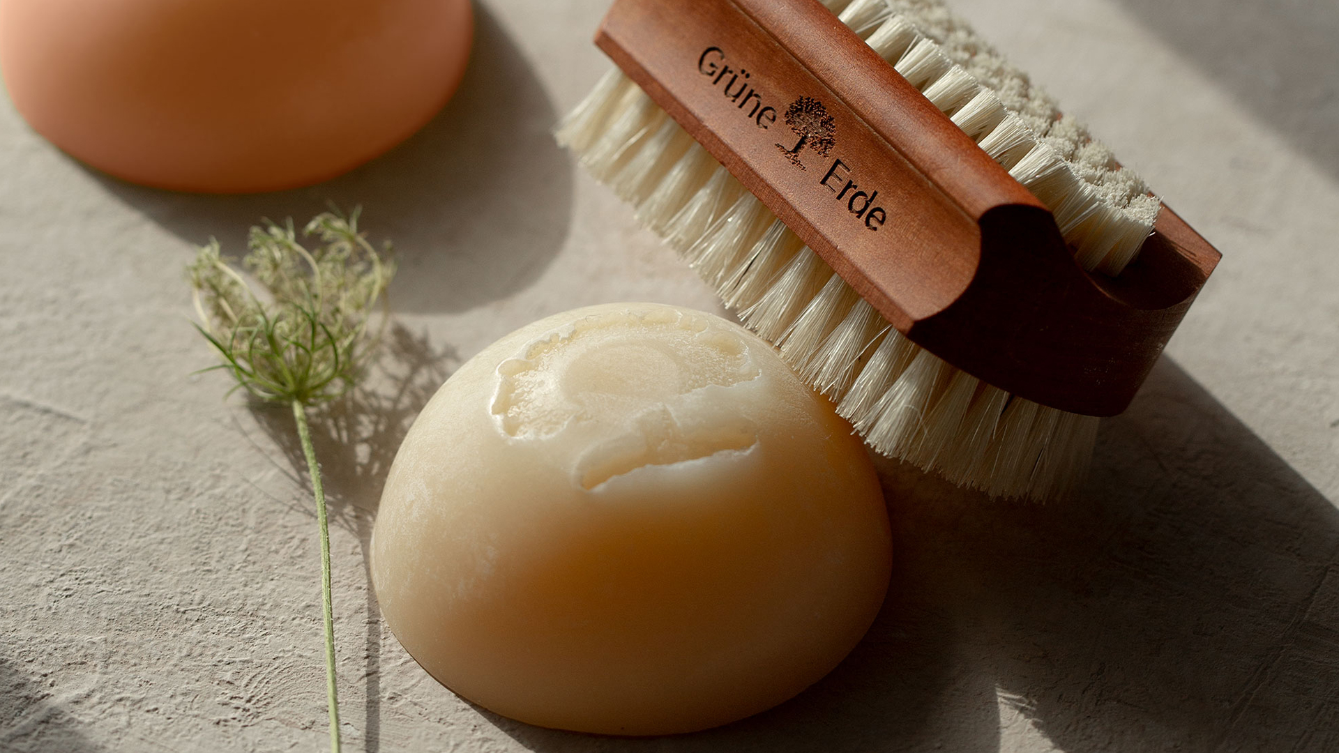 Zwei feste Seifen und ein Bürstchen mit einem dekorativen Blümchen