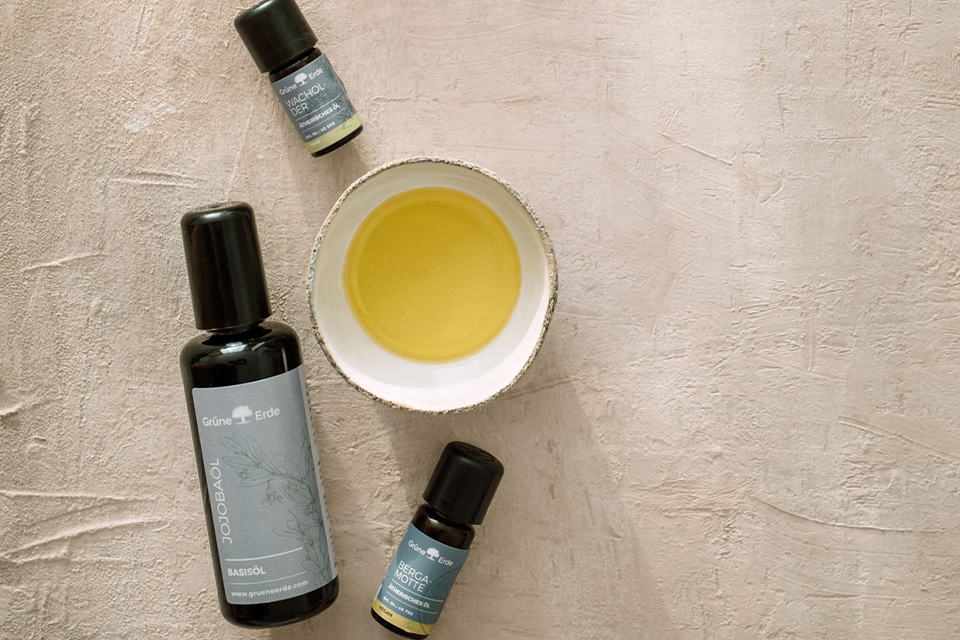 Basisöl und zwei Aromaöle neben einer mit Öl befüllten Schale