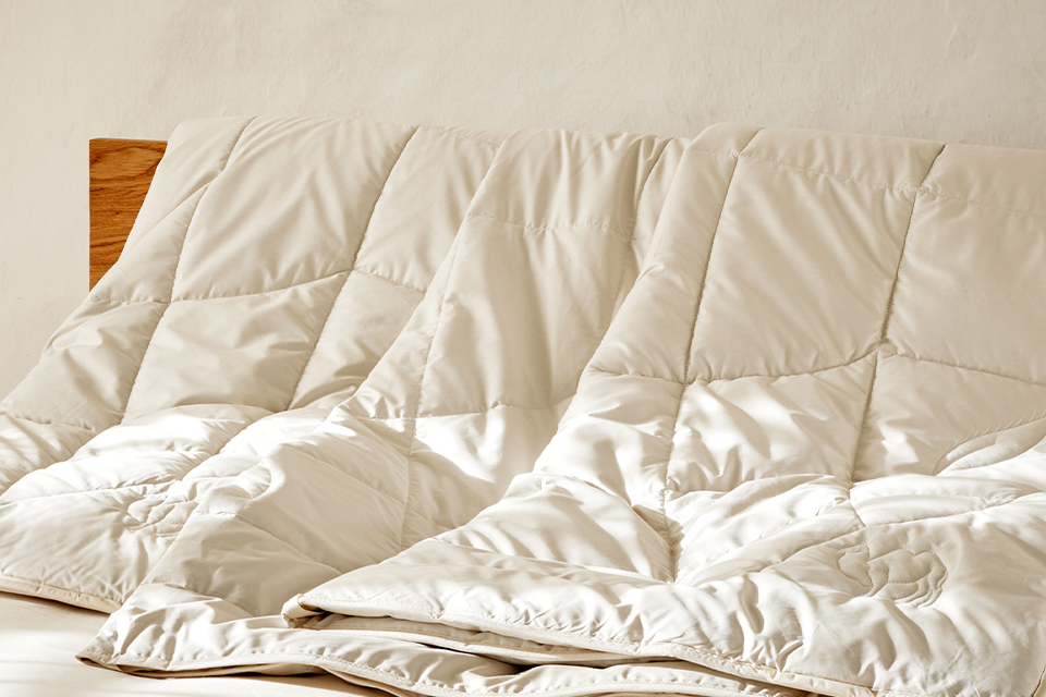 Ökologische Bettdecken auf einem hochwertigen Massivholzbett