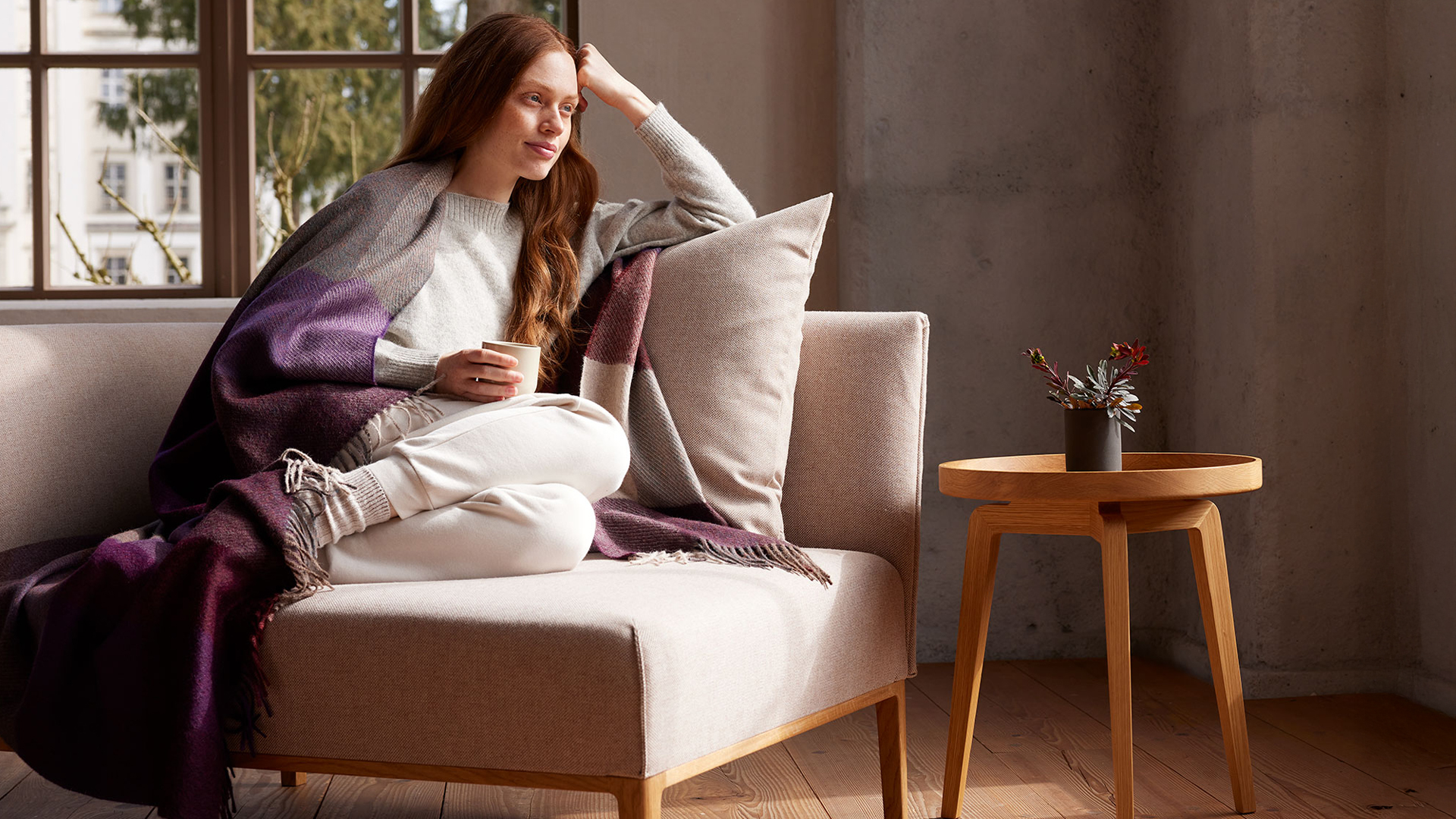 Frau liest entspannt auf Sofa in ruhiger gemütlicher Umgebung