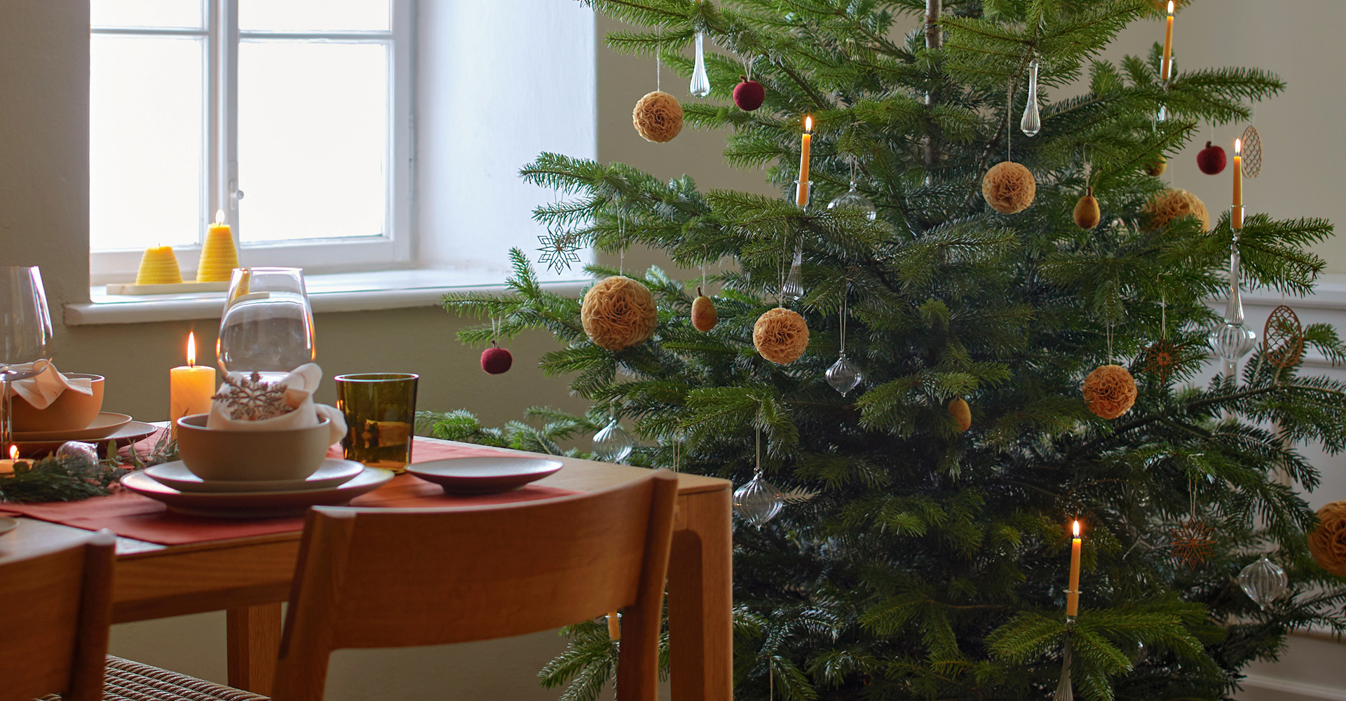 Gedeckter Tisch steht von einem geschmückten Christbaum