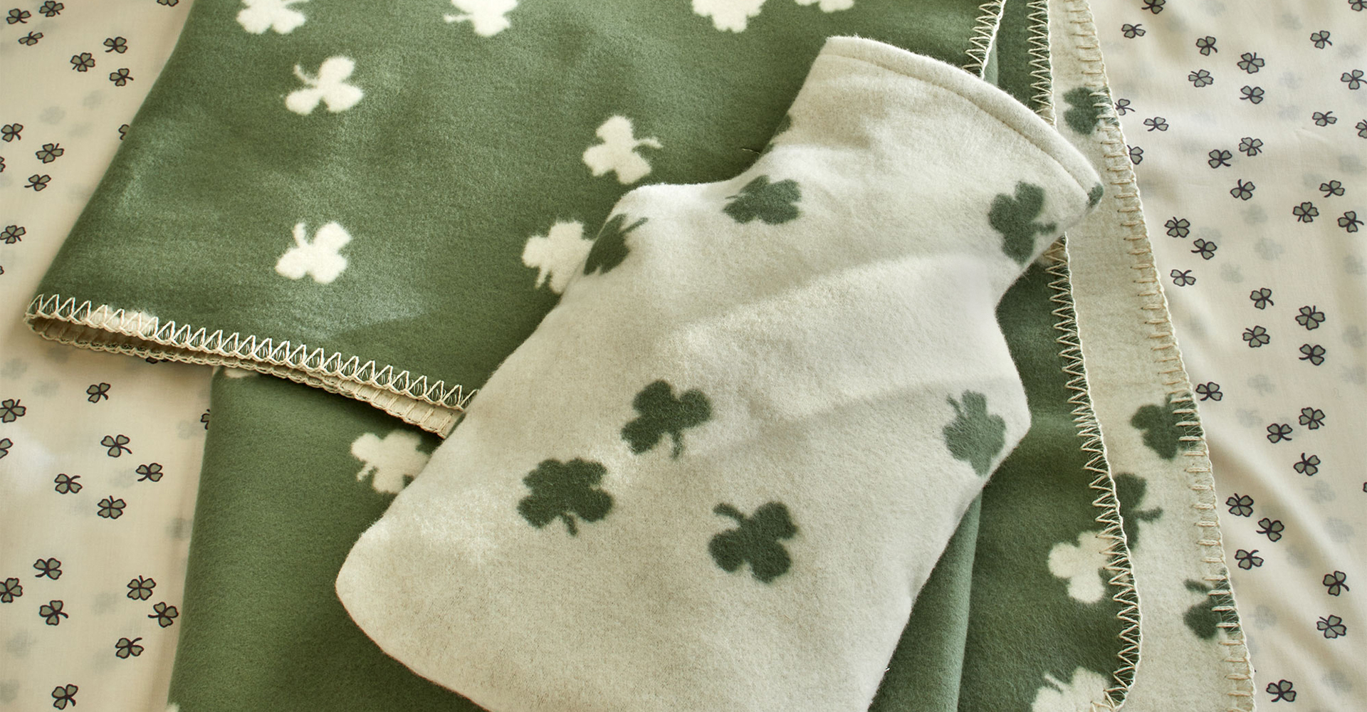 Kuscheldecke und Wärmekissenüberzug mit Kleemuster auf einer Decke liegend
