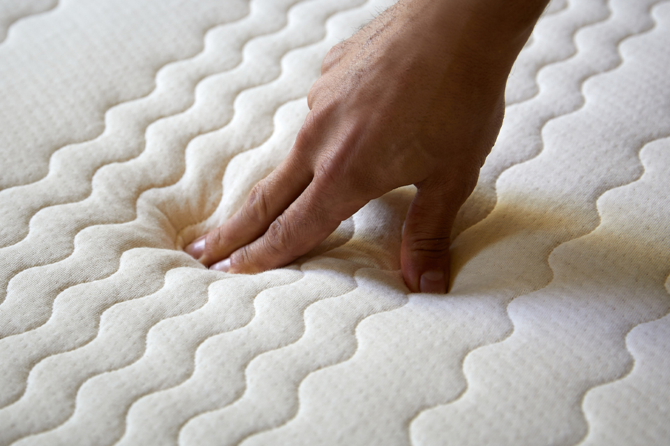 Hand drückt auf Matratze