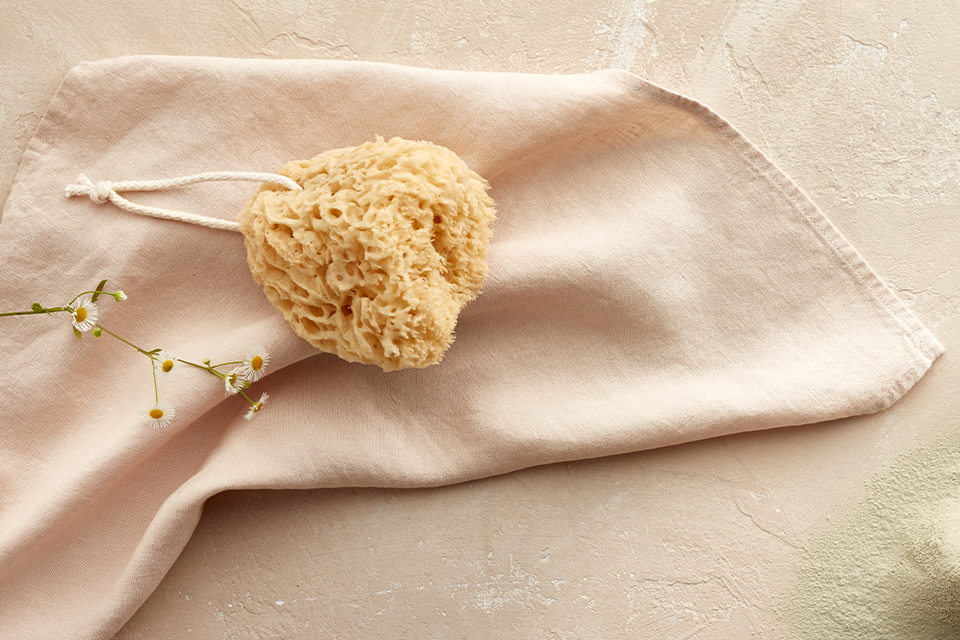 Ein Badeschwamm liegt auf einem hellen tuch