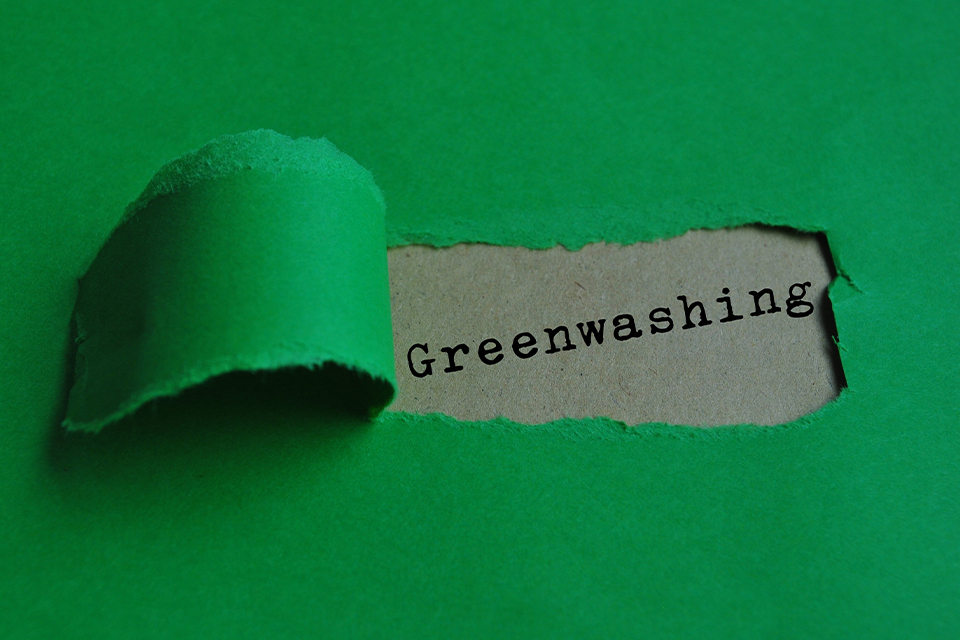 Grünes Papier ist aufgerissen dahinter steht Greenwashing geschrieben