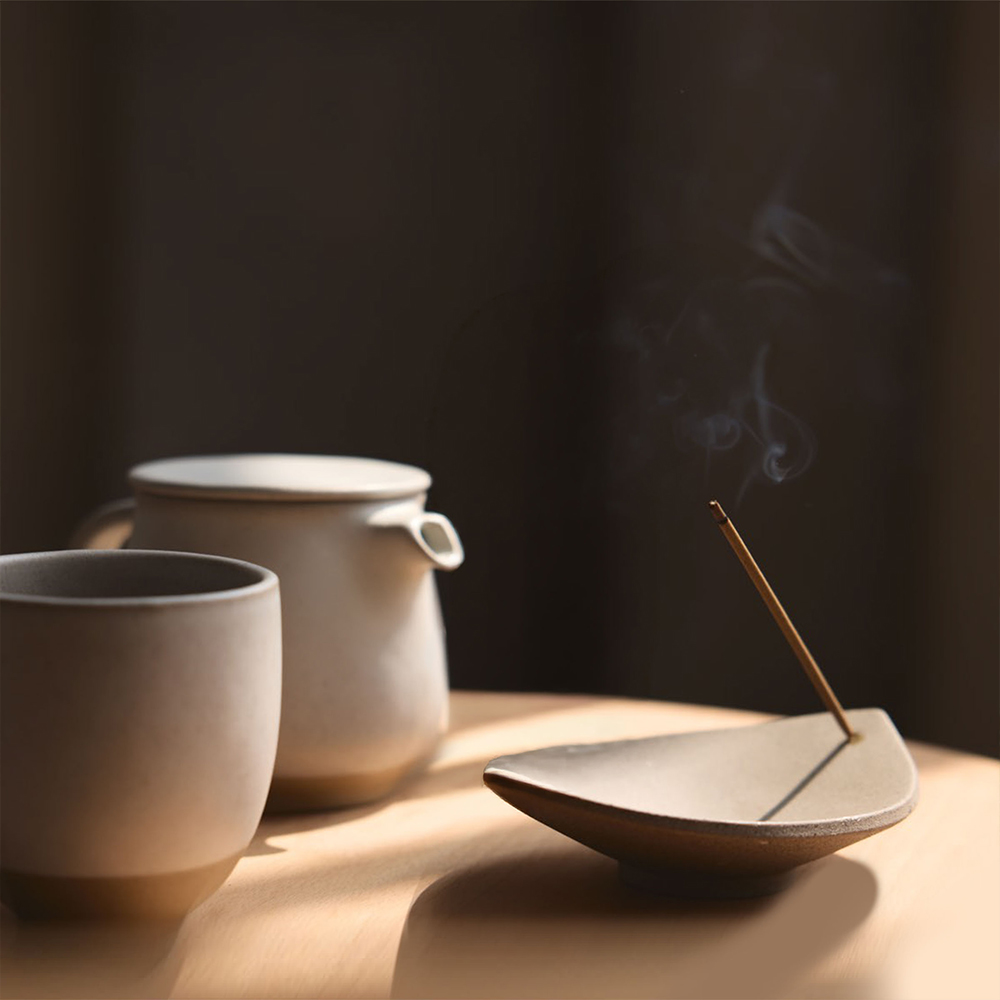 Teekanne und Tasse neben einem Räucherstäbchenhalter