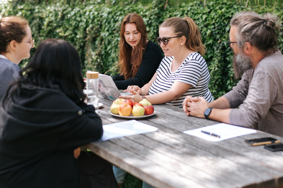Teammeeting im Freien mit mehreren Personen am Tisch