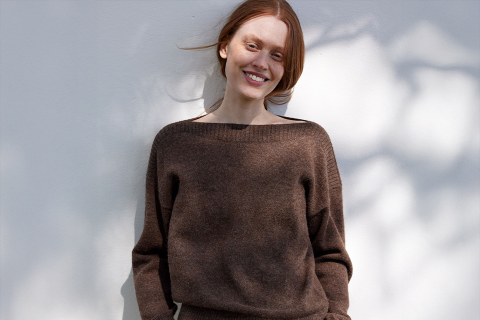 Lächelnde Frau im braunen Pullover im weichen Licht