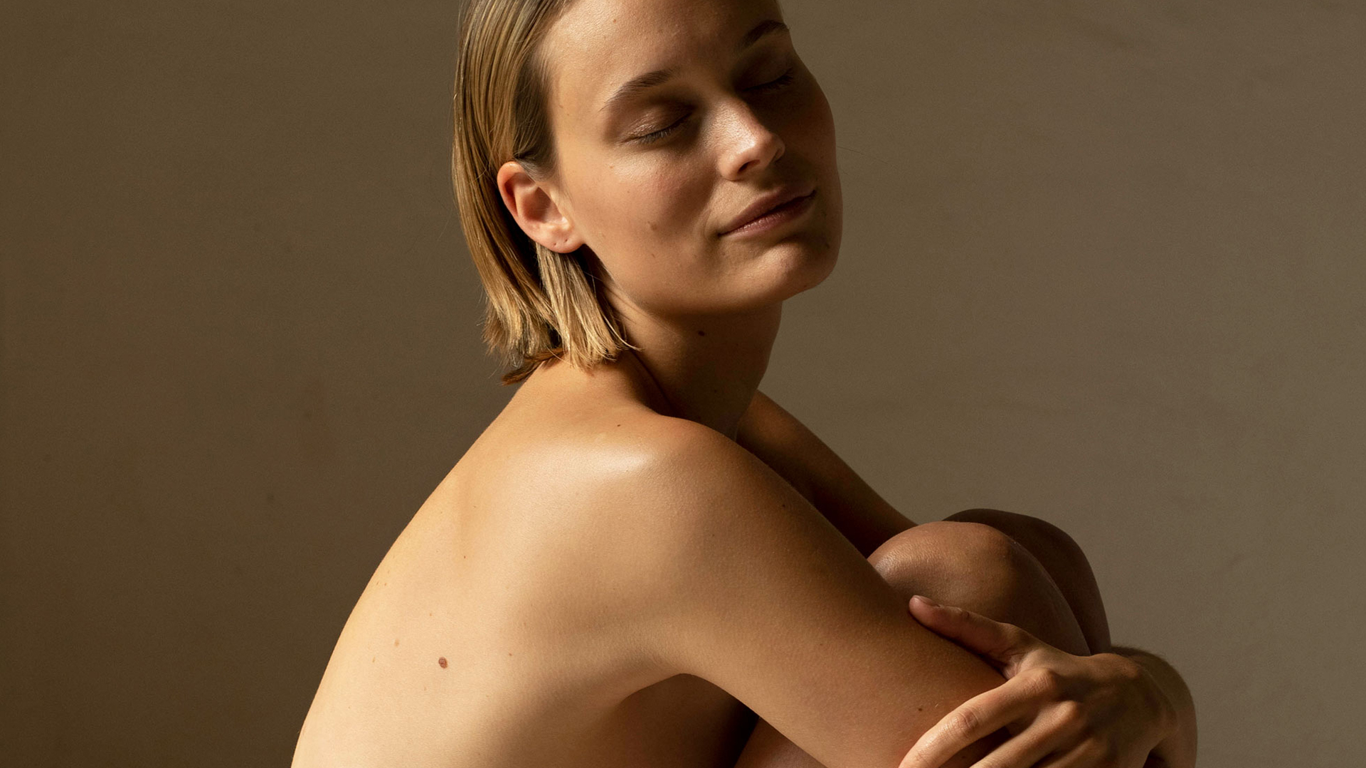 Frau umarmt sich selbst und zeigt gepflegte Haut im warmen Licht