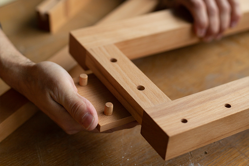 Hand steckt Holzverbindung zusammen