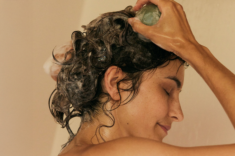 Frau wäscht ihre Haare mit festen Haarshampoo