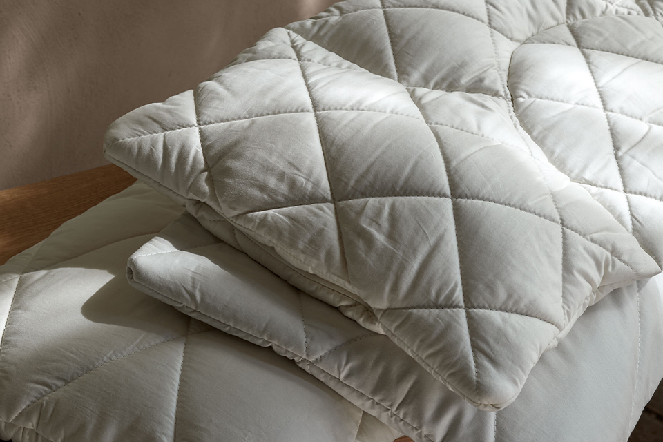 Drei hochwertige Kopfkissen auf einer Holzbank